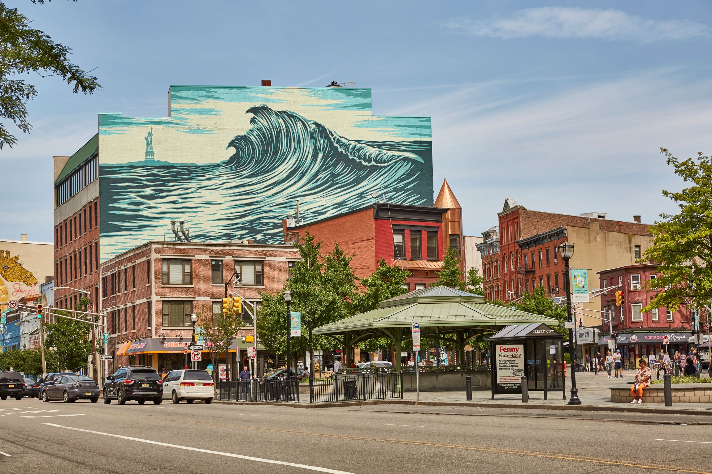Street view of brick buildings in the city with a large mural of a wave above