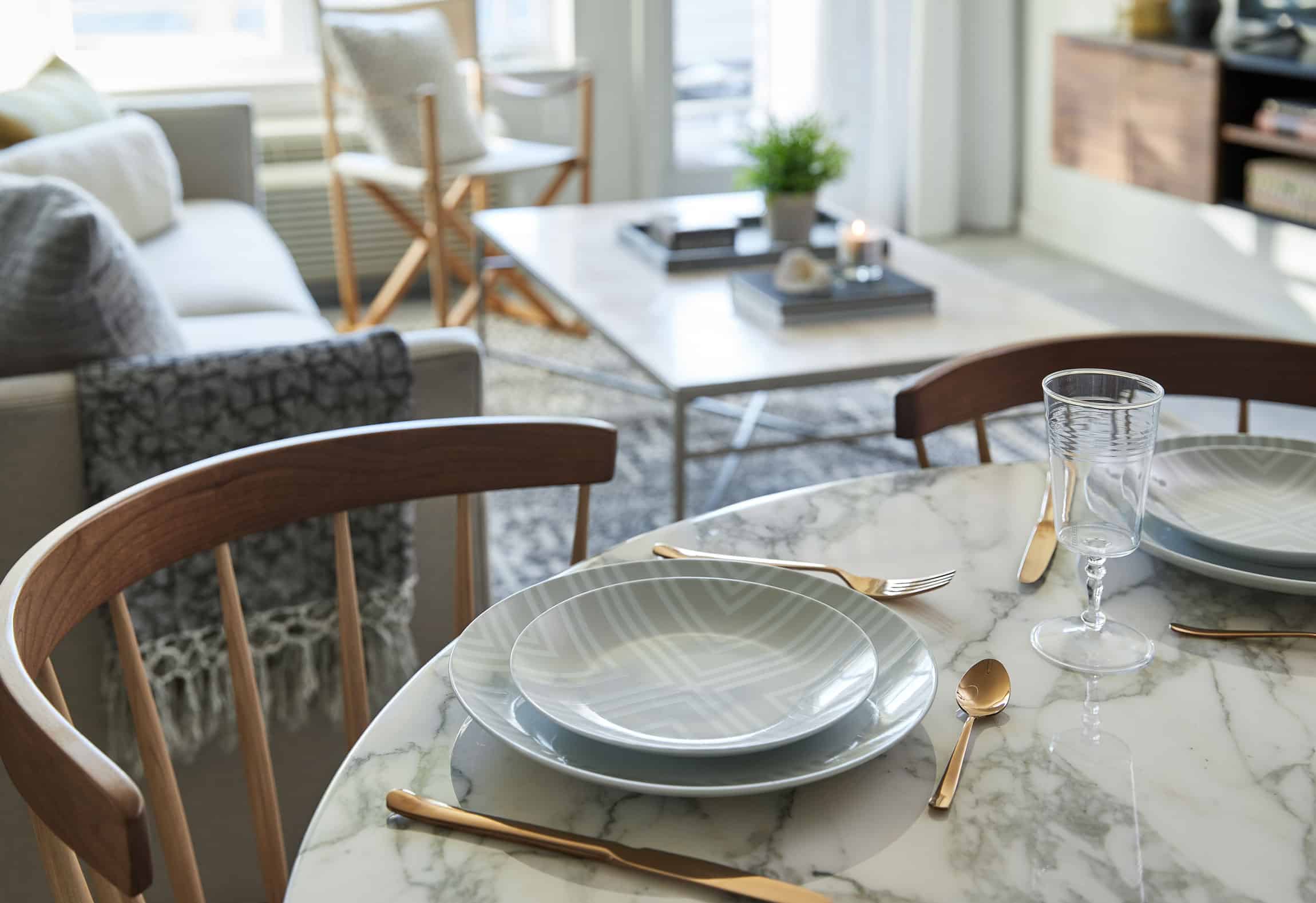 close up of table settings on round marble dining table with living room in the background