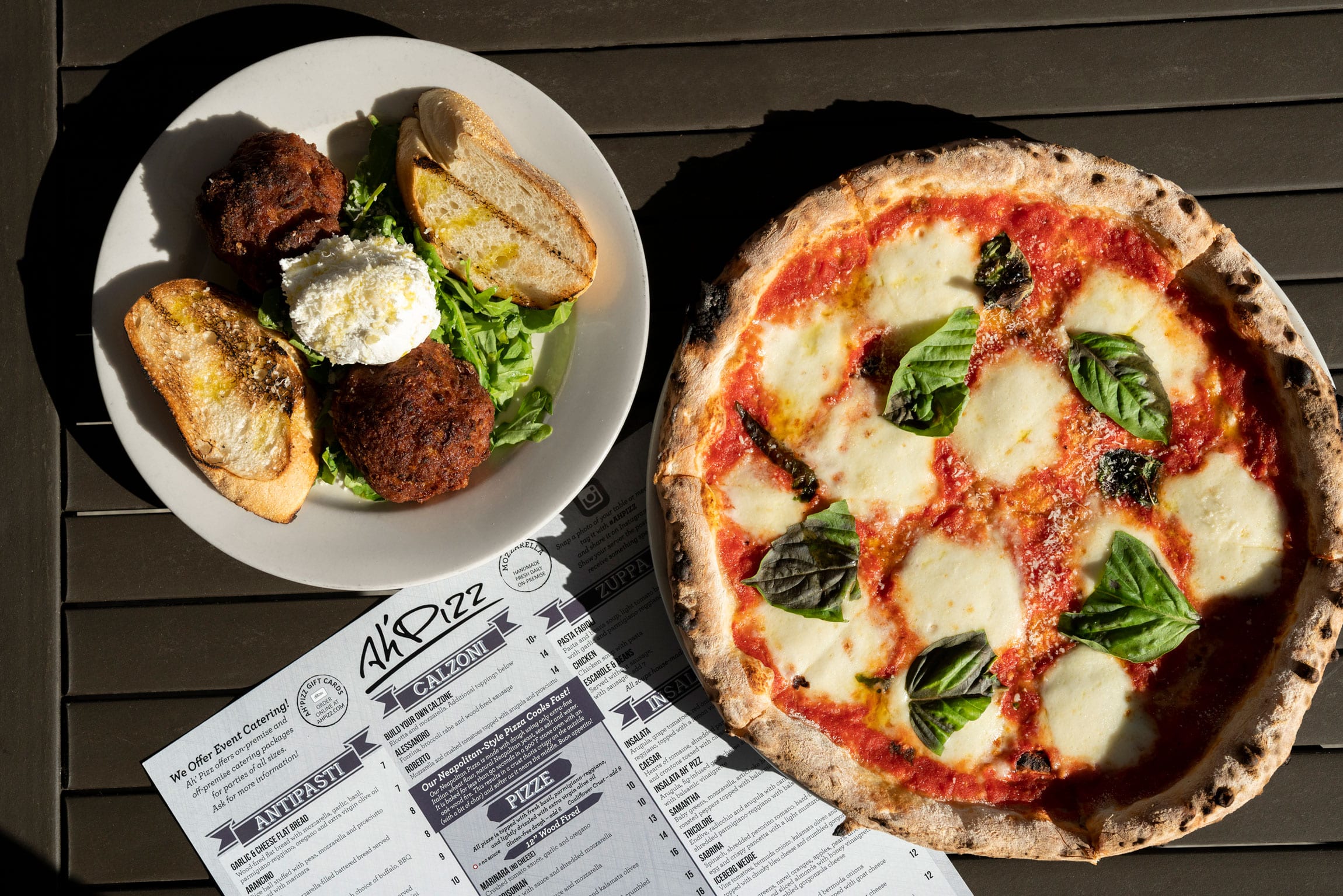 margherita pizza topped with fresh basil and arancini with cheese and grilled bread